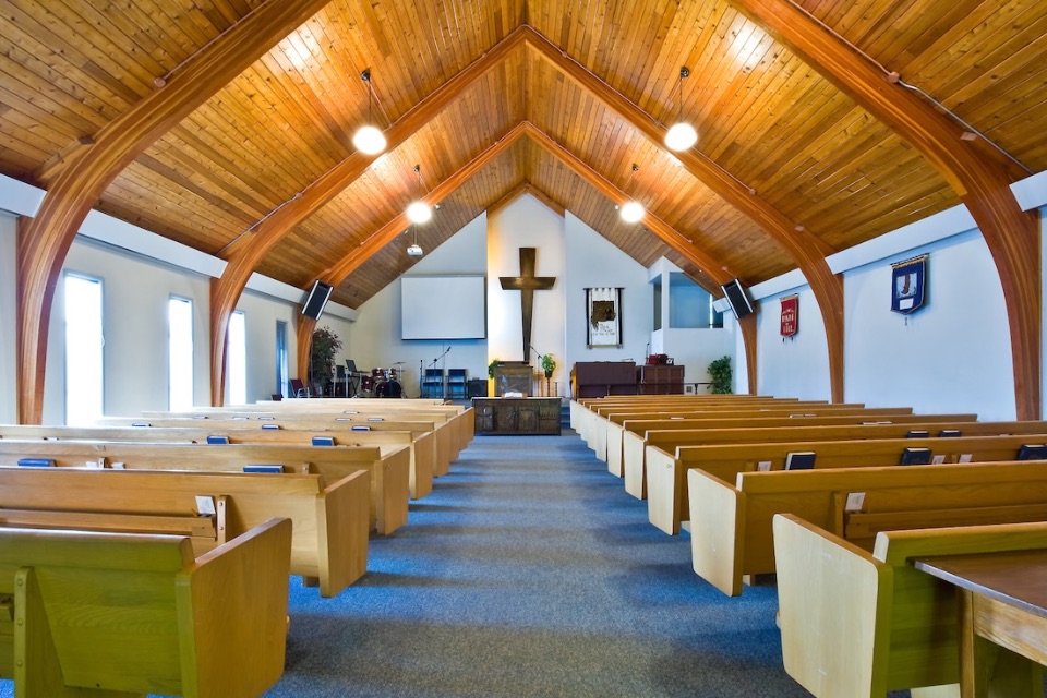 Interior of older church with wood ceiling and pews.